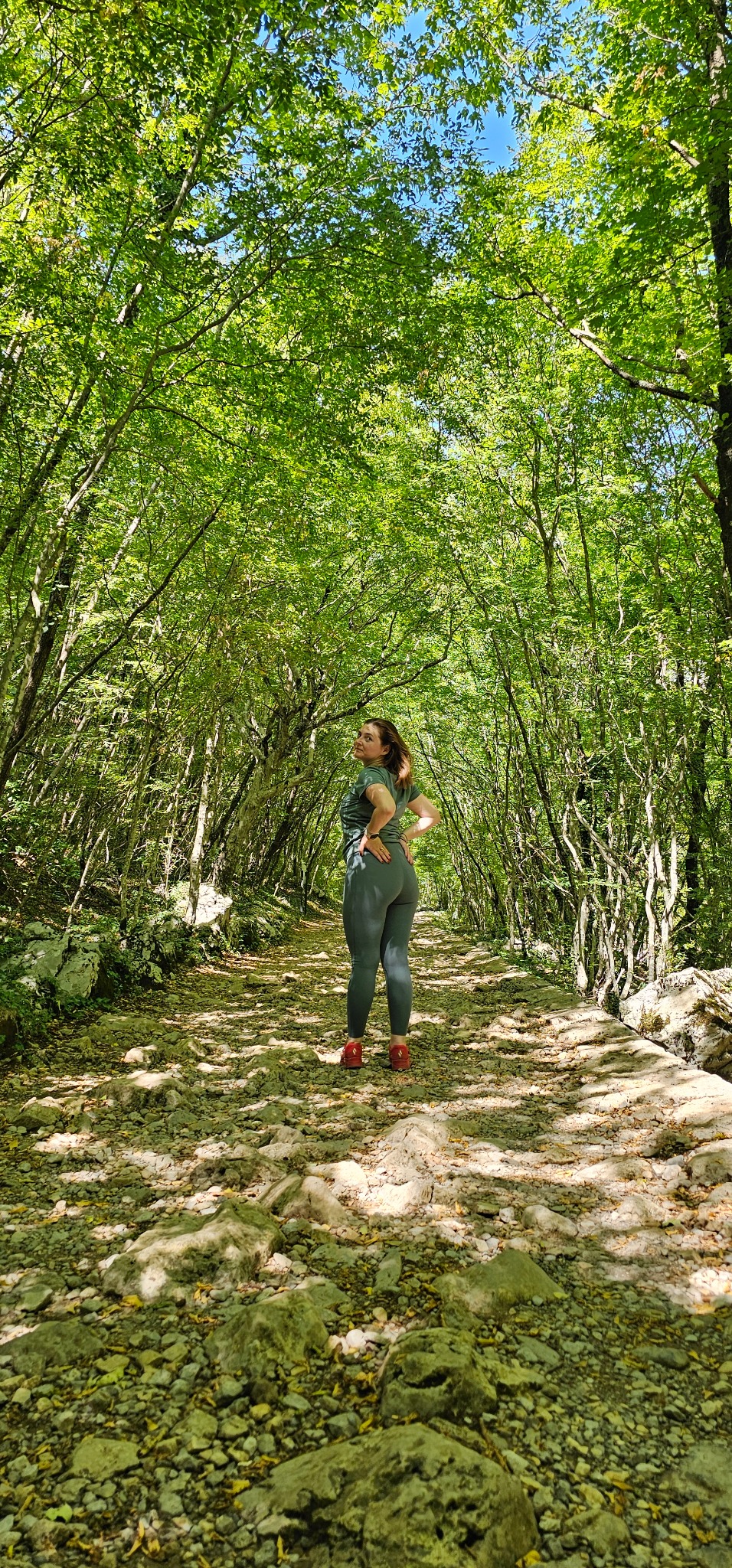Ana Balen walking through a sunlit forest